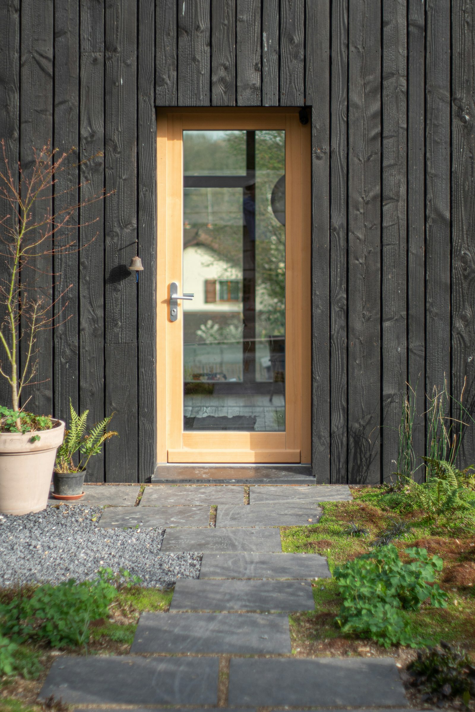 Oak front door with glazed panel in dark cladding